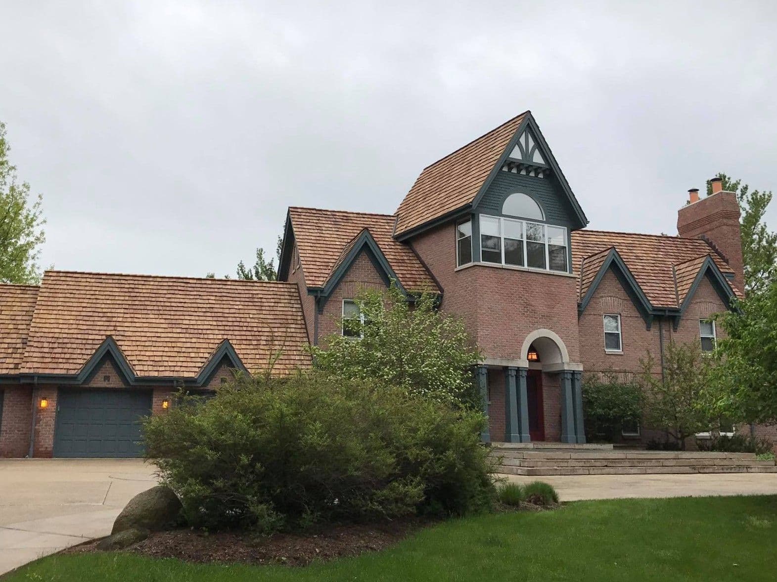 A large brick house with new shake roofing.