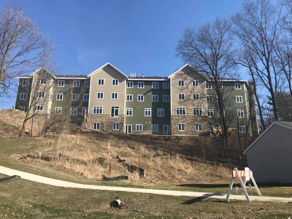 A large commercial apartment building with alternating sections of tan and green siding.